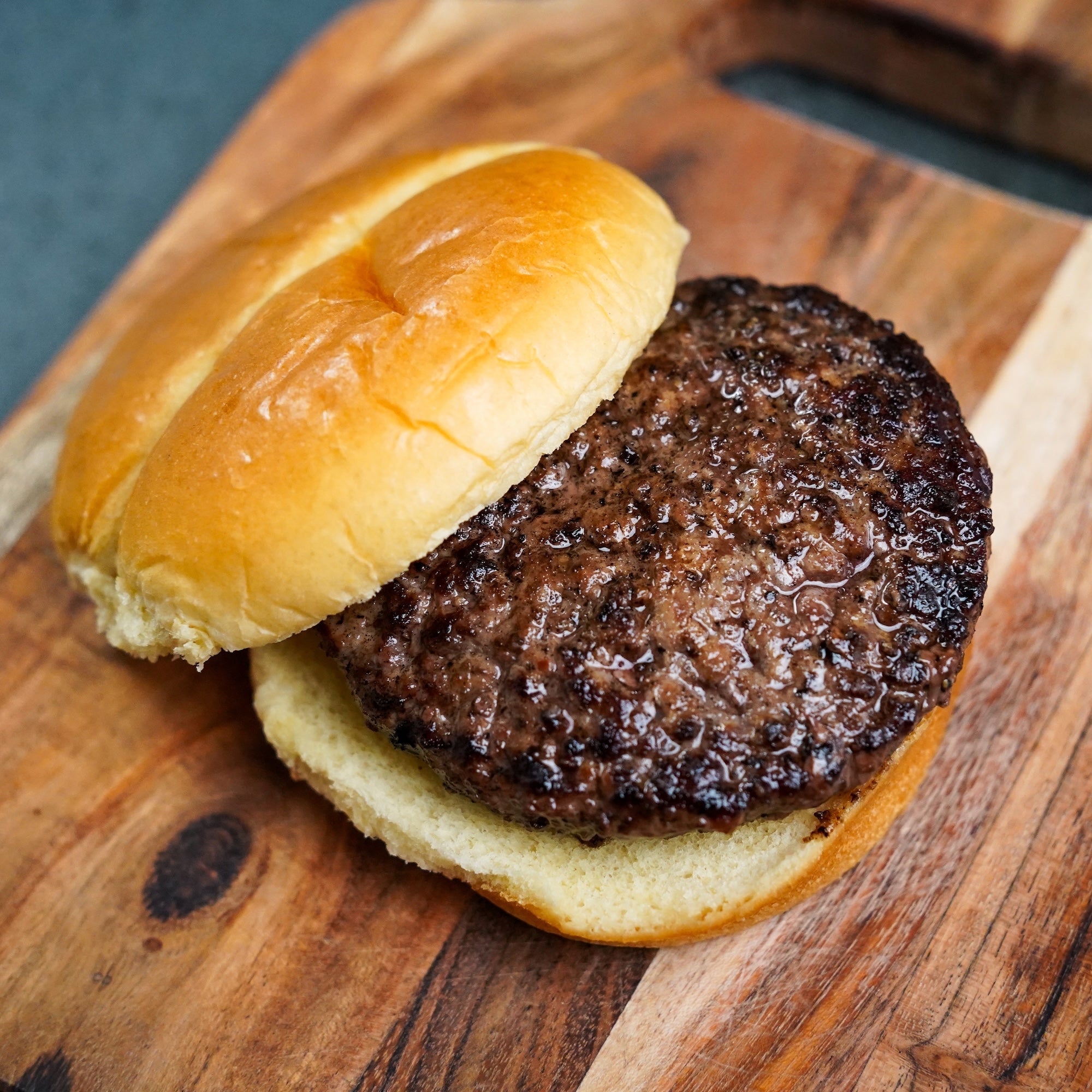 cooked burger patty on bun on wood surface