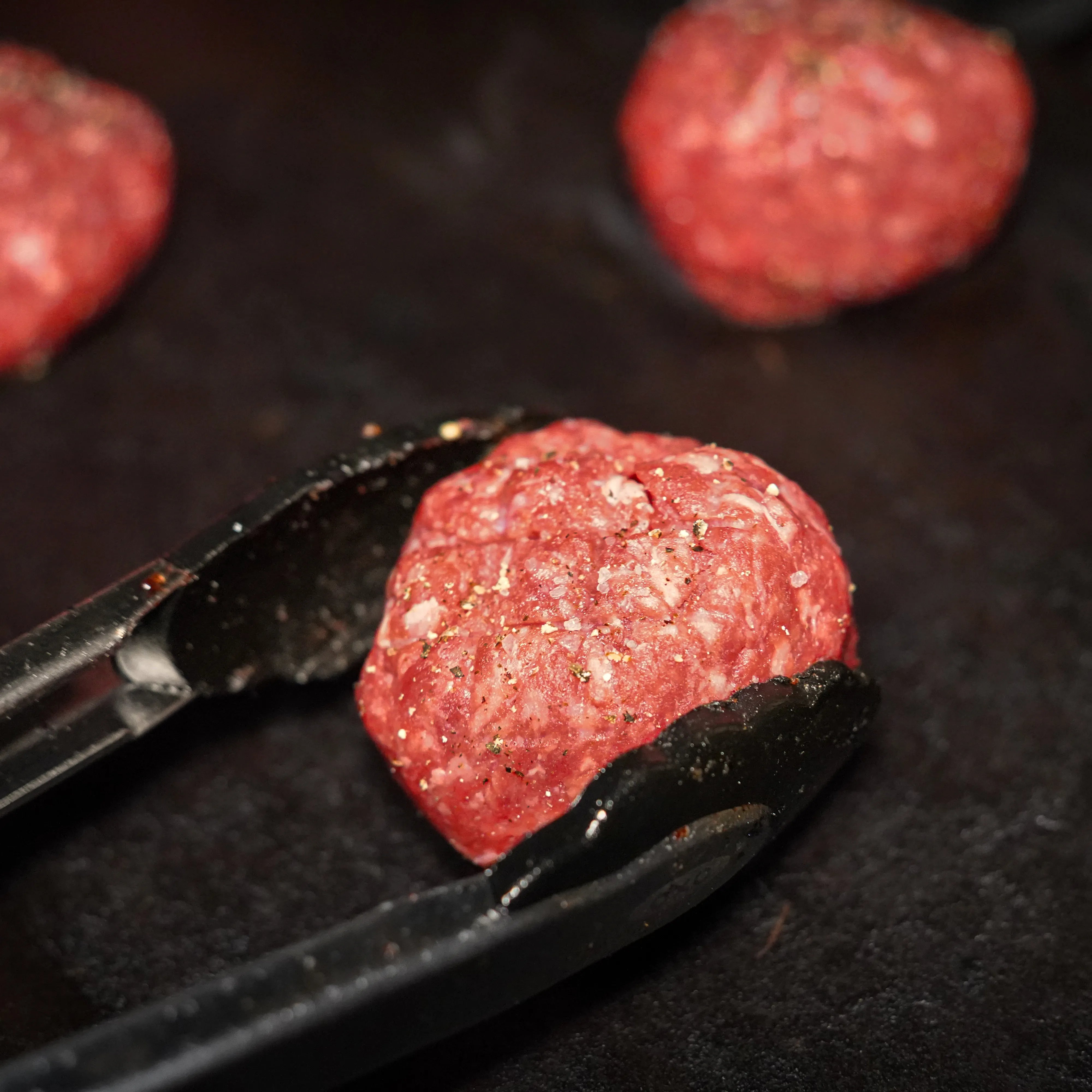Raw burger balls going on grill