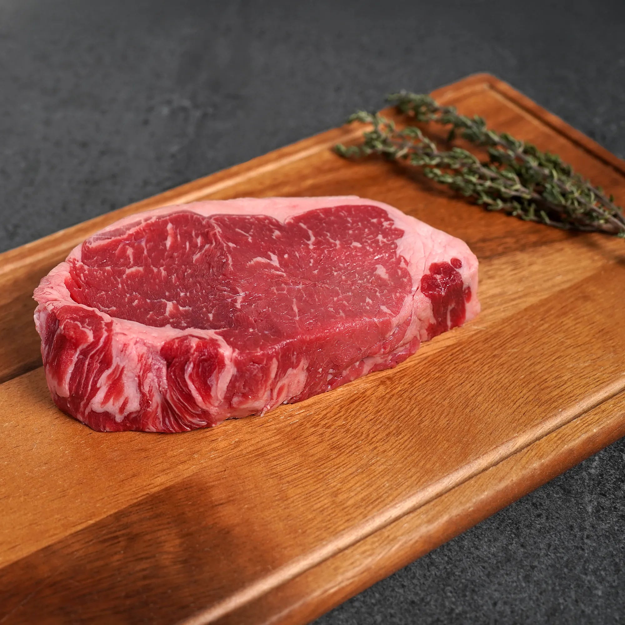 Raw steak on a wooden cutting board with a dark background