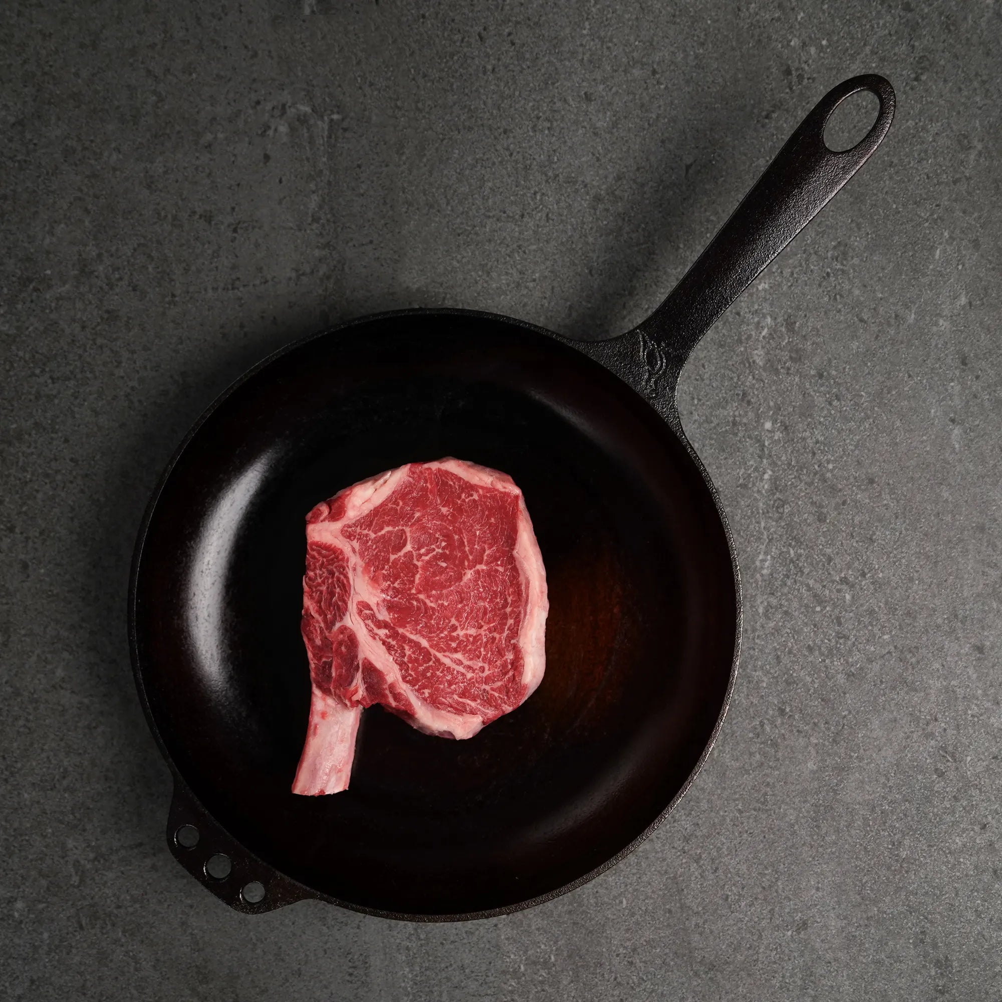 Raw bone in steak on black iron pan