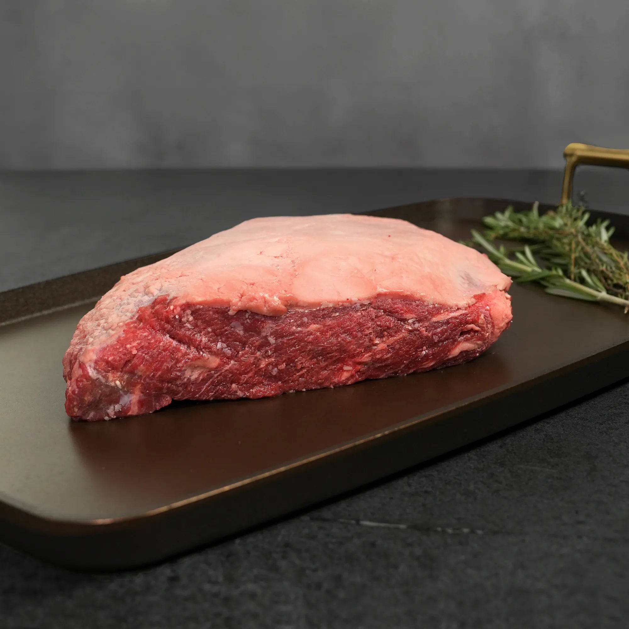 Raw beef on a dark surface with rosemary