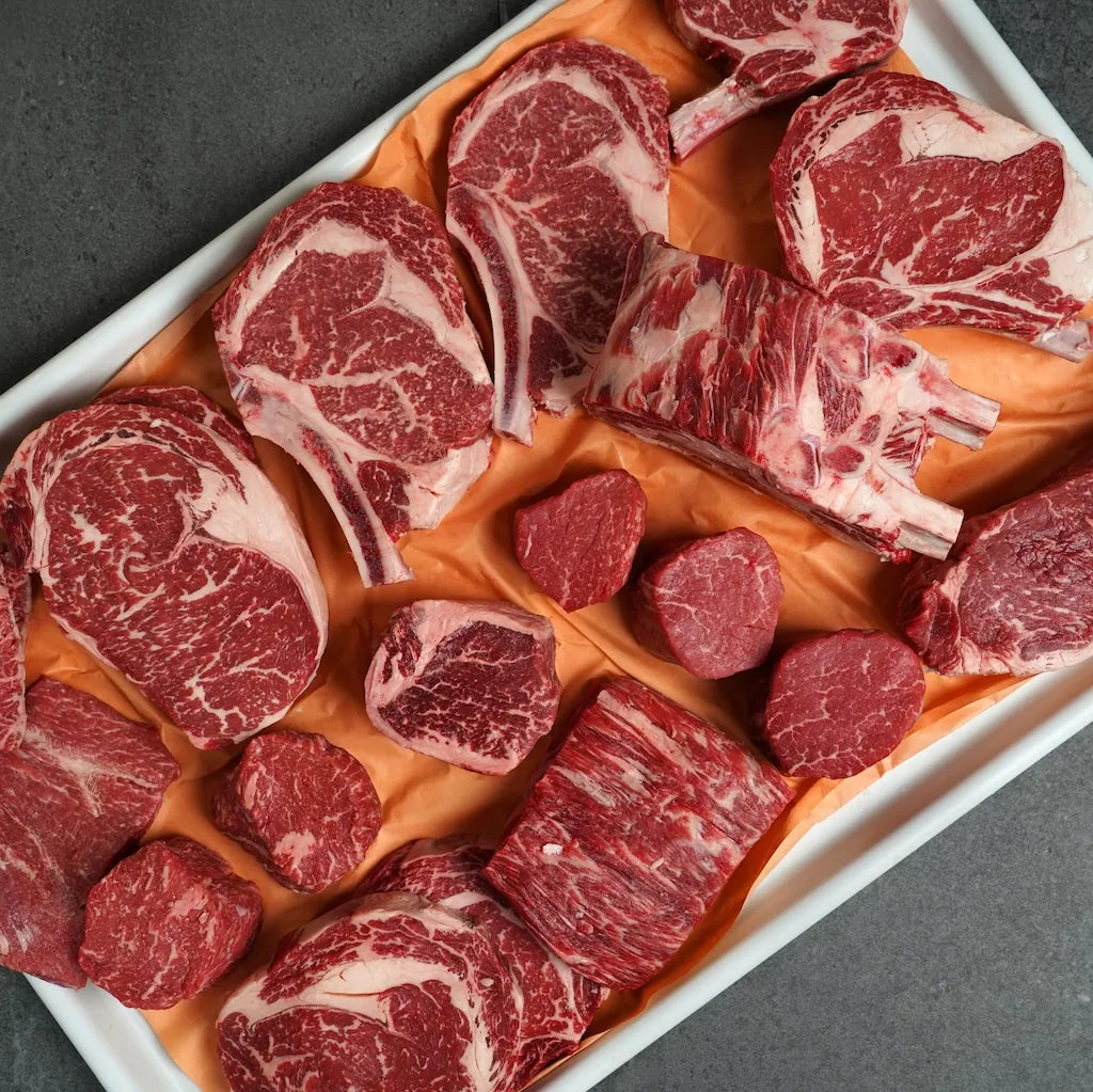 Assorted raw red meat on a white tray with an orange cloth
