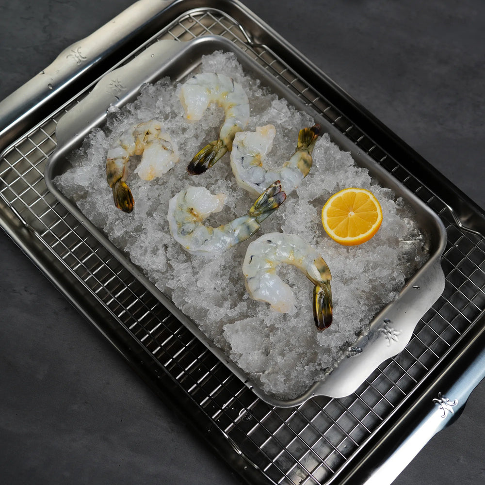 Raw Foley Black Tiger Shrimp on ice in a silver sheet pan with a lemon