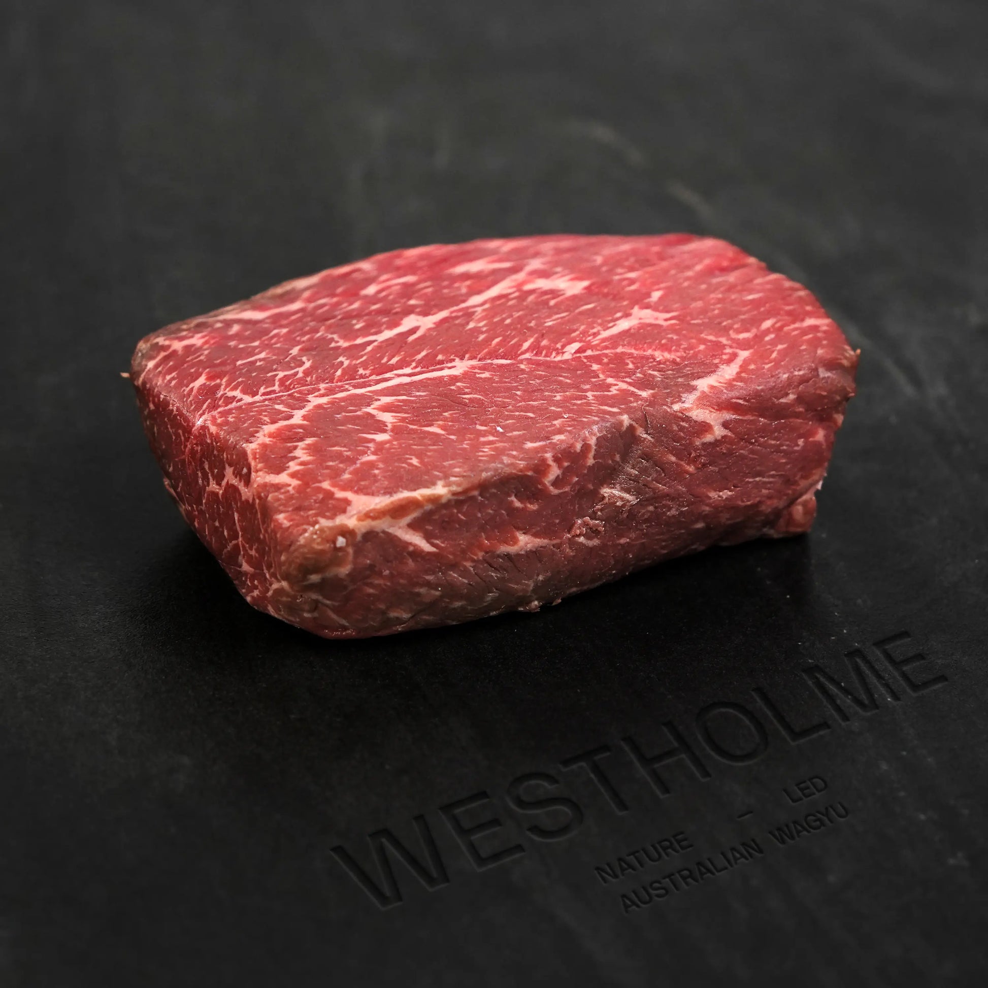 Australian Wagyu Center Cut Top Sirloin Steak on a branded cutting board; thick-cut, well-marbled, showcasing the rich texture and premium quality of Australian Wagyu beef.