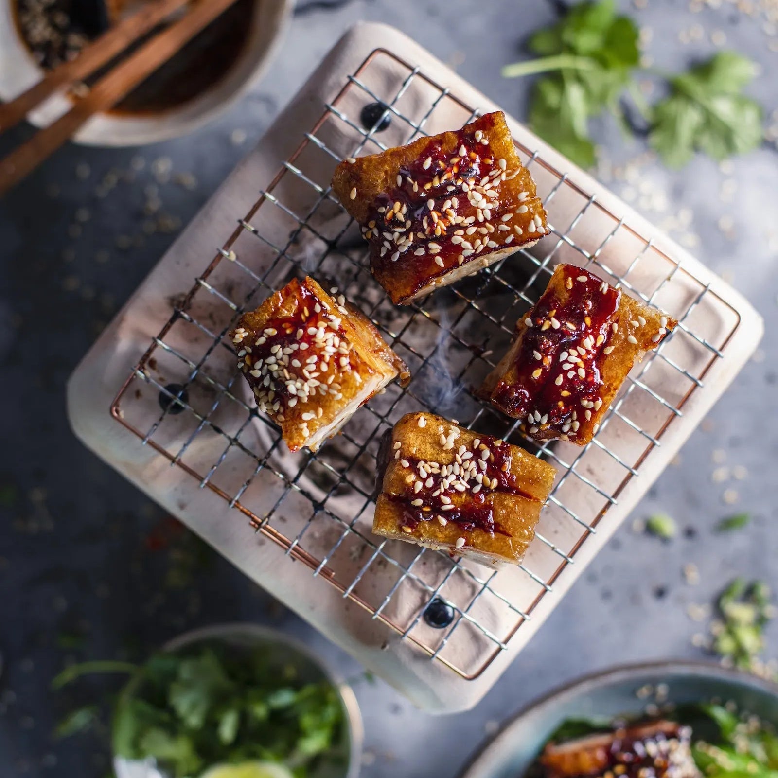 Sesame seeds on top of a dish with a bowl of sauce and chopsticks in the background.