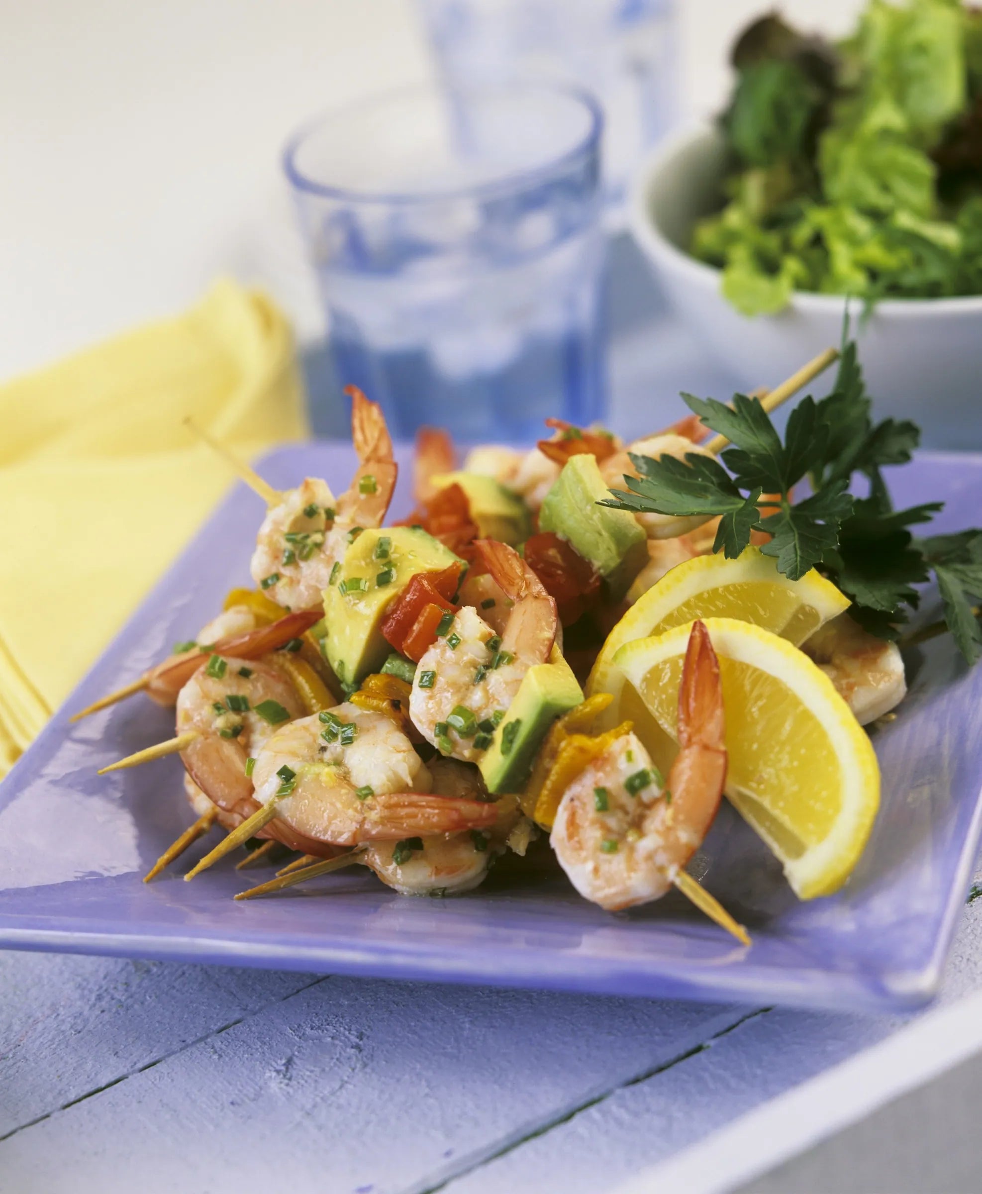 Shrimp on skewers on blue plate with fruit and vegetables